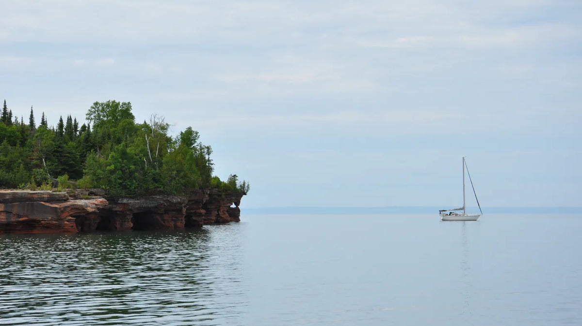Apostle Islands - A sailboat on calm Lake Superior water off the sandstone edge of Devils Island