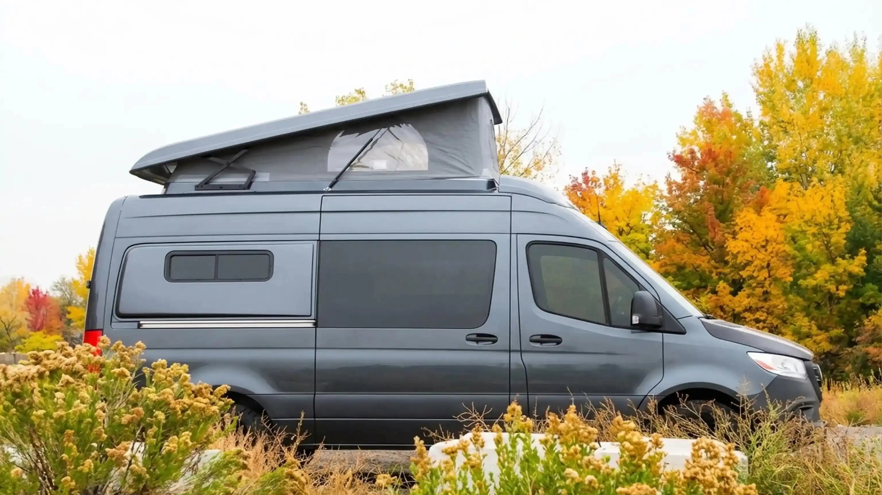 best camper van for tall people - Gray camper van parked with elevated roof for camping