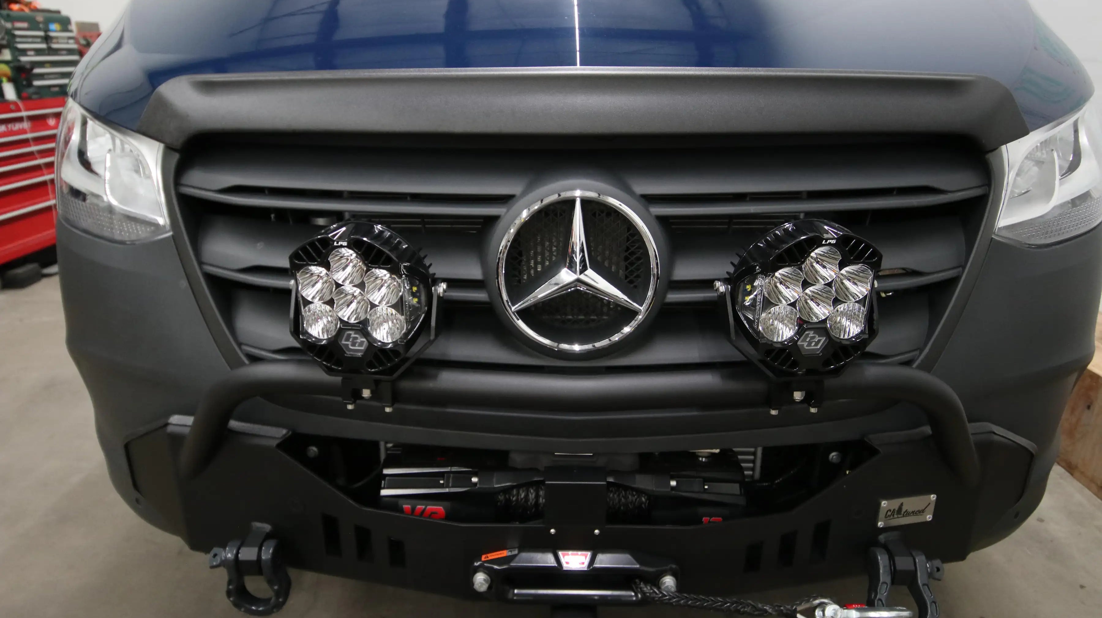 build mercedes - This image shows the front exterior of a Mercedes-Benz Sprinter van inside a gar