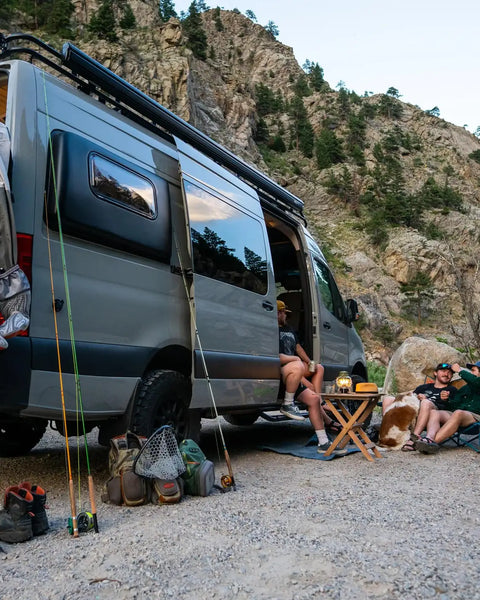 camp conversion - Friends camping by van with fishing gear and dog