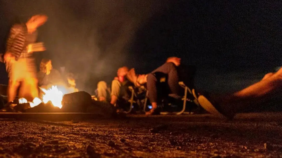 Campfire Games - Campers relaxing around a campfire at night