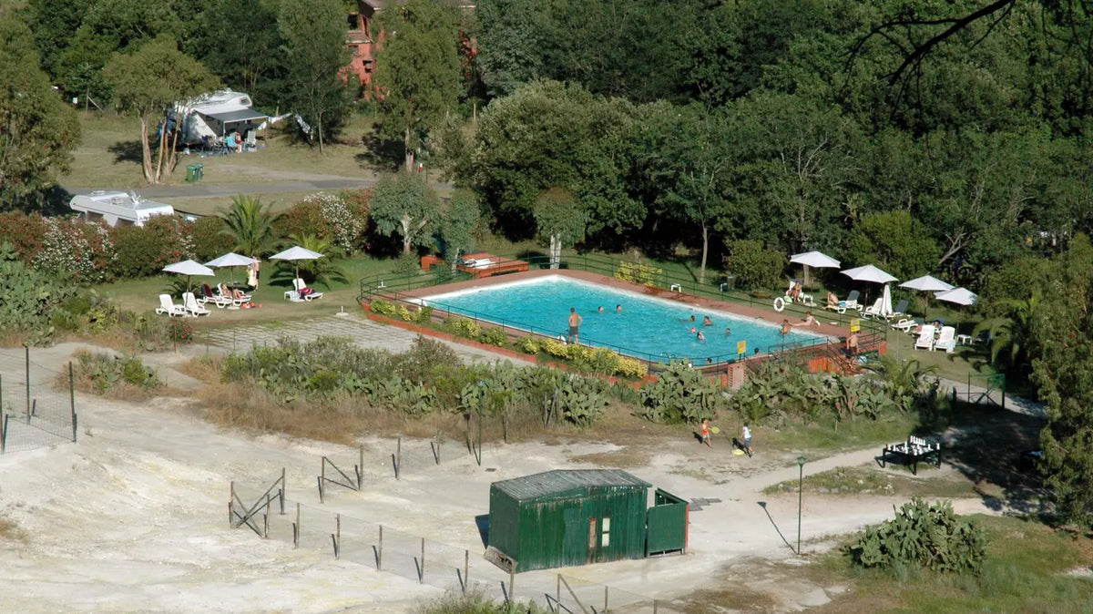 Campgrounds with pools near me - A campground swimming pool with loungers, set below wooded RV and tent sites