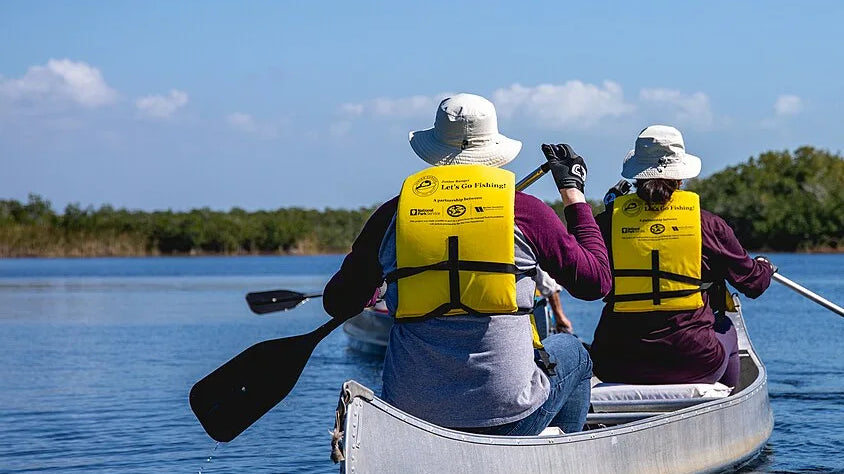 Kayak camping gear list - paddlers underway in life jackets on a calm waterway