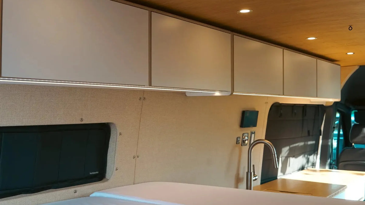 Sprinter Van Interior Ideas - A Vansmith Sprinter interior with upper cabinets, a bed, and a galley with sink
