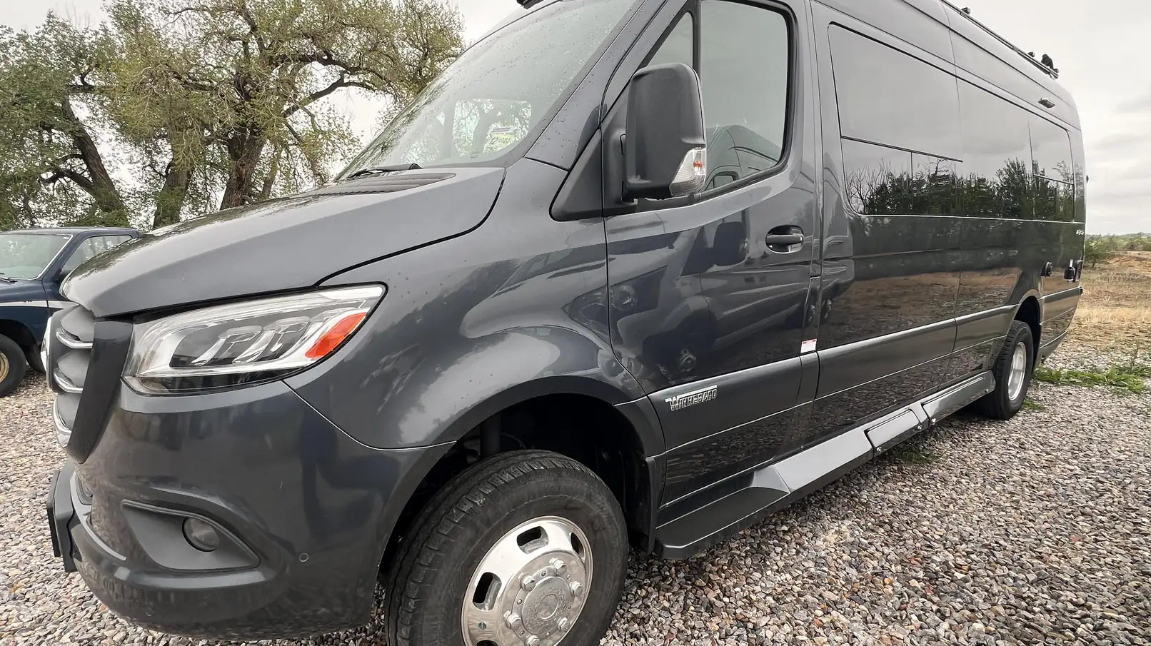 white mercedes sprinter van - The image shows the exterior of a black Mercedes-Benz Sprinter van with a high r