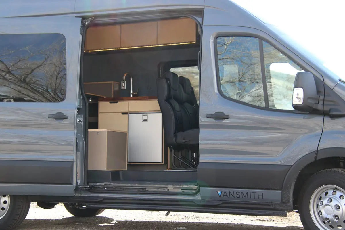 View Through Open Sliding Door of Kitchen Galley, Upper Cabinets and Chairs of The Vansmith Family XL Long Wheelbase Van Conversion