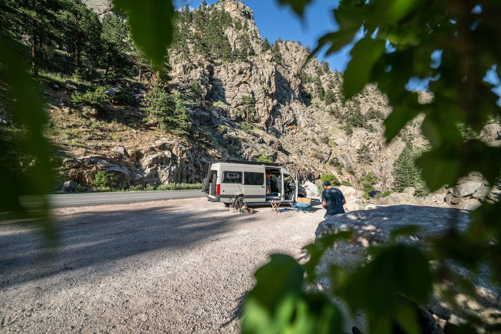 Sustainable Sprinter Van Conversion by The Vansmith with Camping Gear Outside in Front of Rock Wall