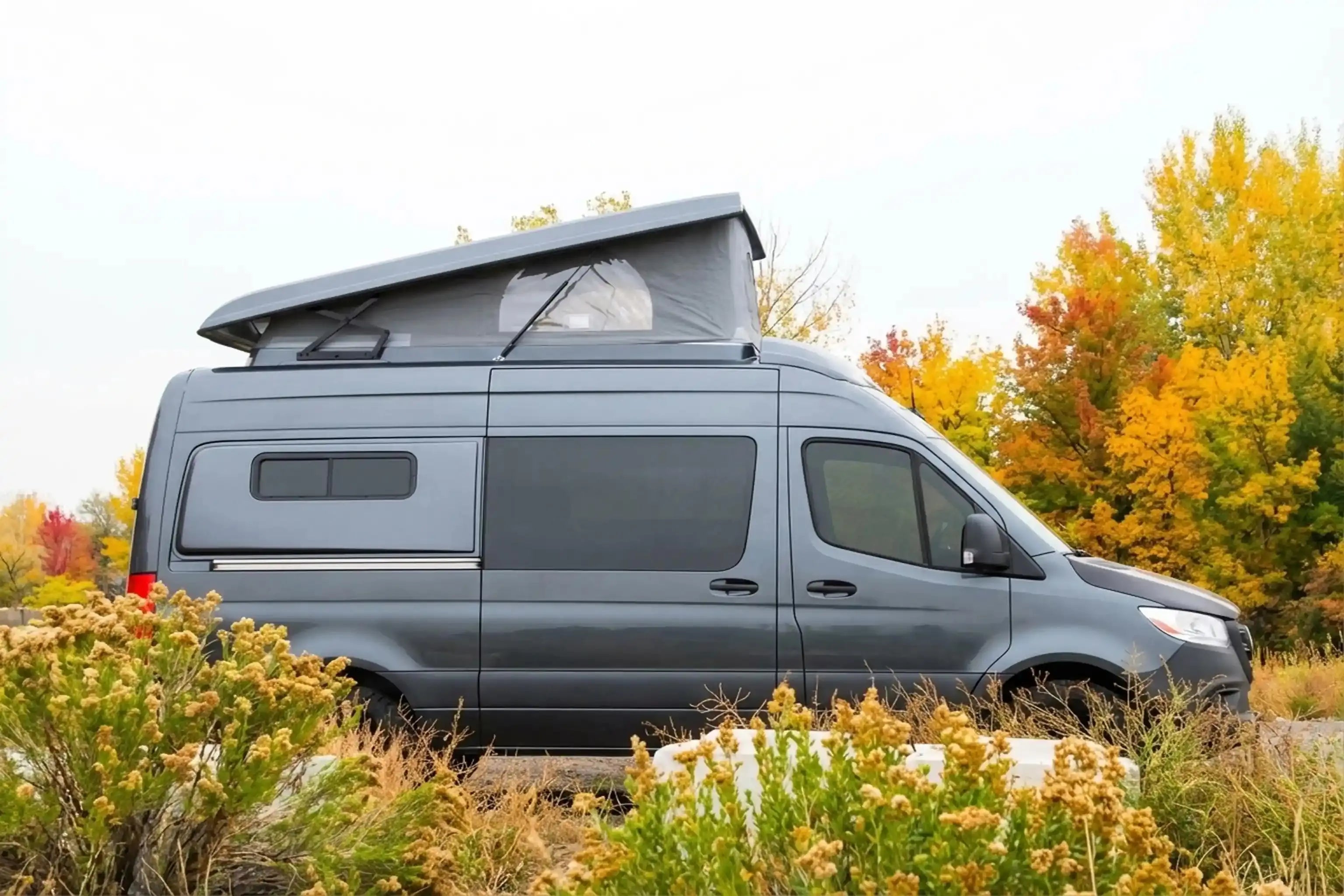 best camper van for tall people - Gray camper van parked with elevated roof for camping