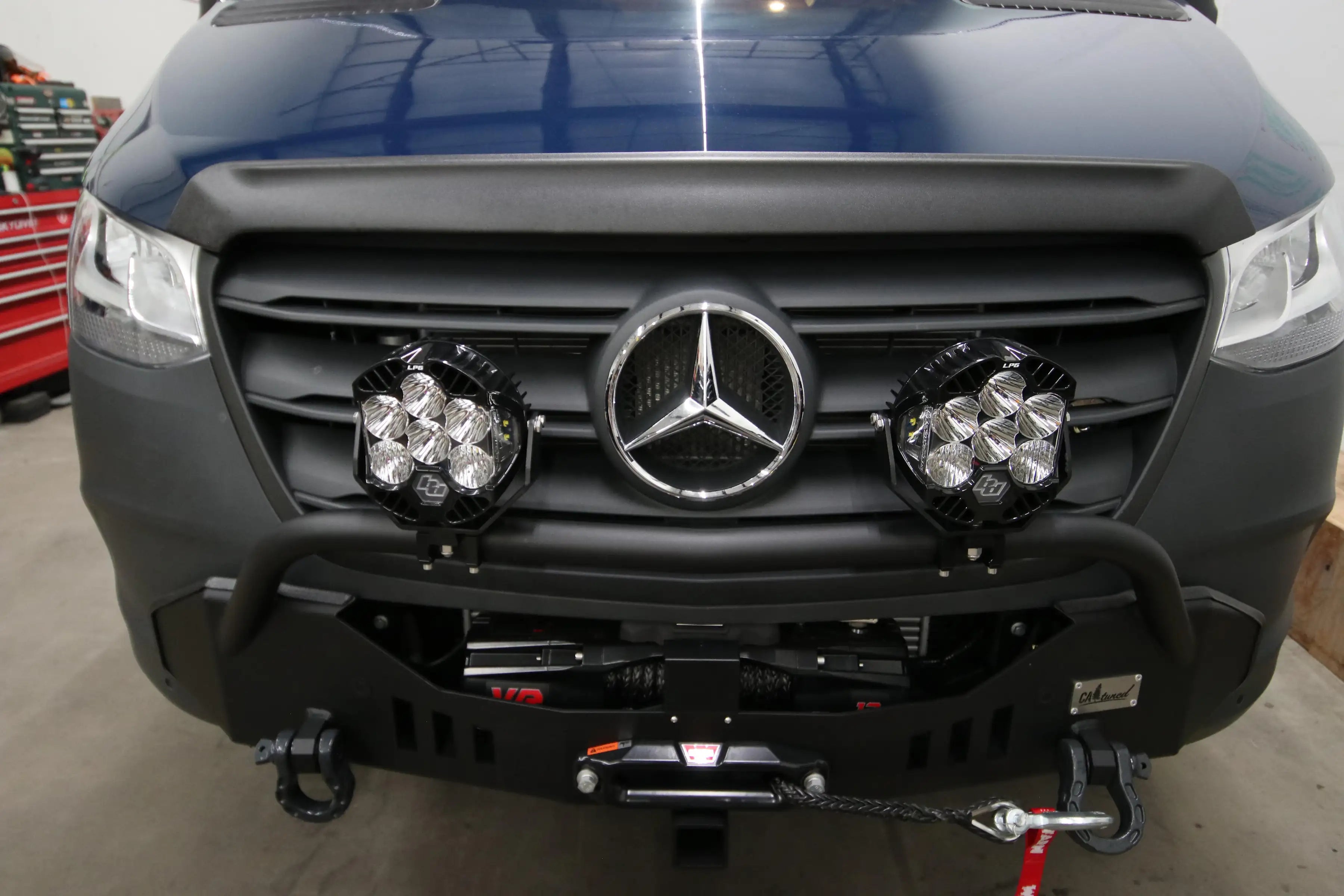 build mercedes - This image shows the front exterior of a Mercedes-Benz Sprinter van inside a gar