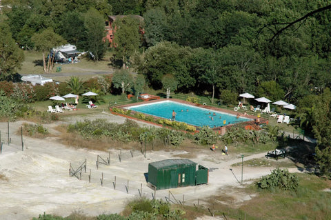 Campgrounds with pools near me - A campground swimming pool with loungers, set below wooded RV and tent sites