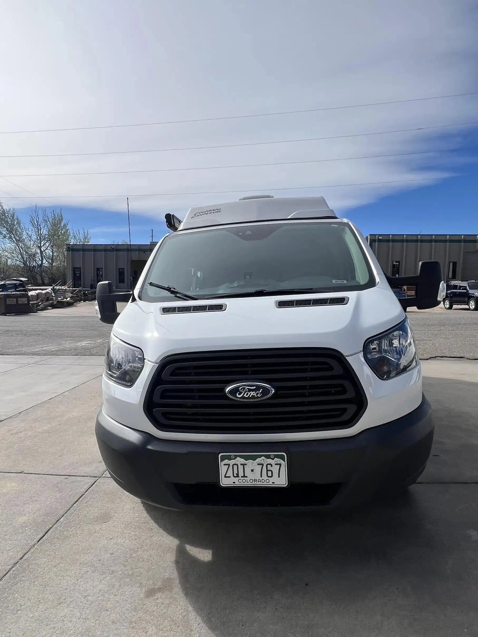 colorado camper van - The image shows the front exterior of a white Ford camper van with a high roof e