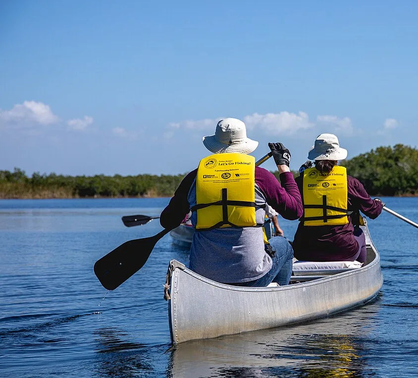 Kayak camping gear list - paddlers underway in life jackets on a calm waterway