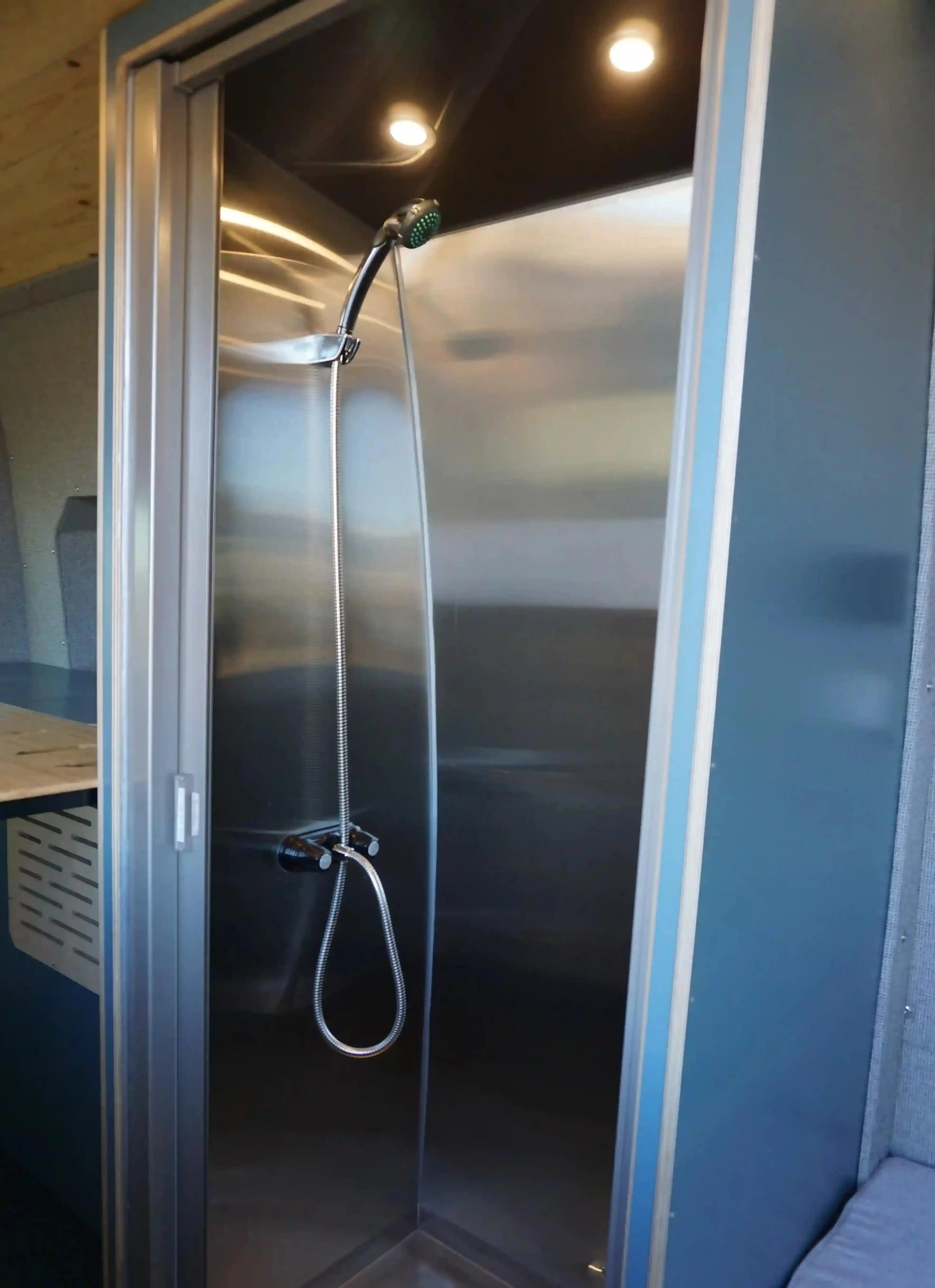 Natural Shampoo for Camping - The shower stall with a handheld showerhead inside a Vansmith camper van