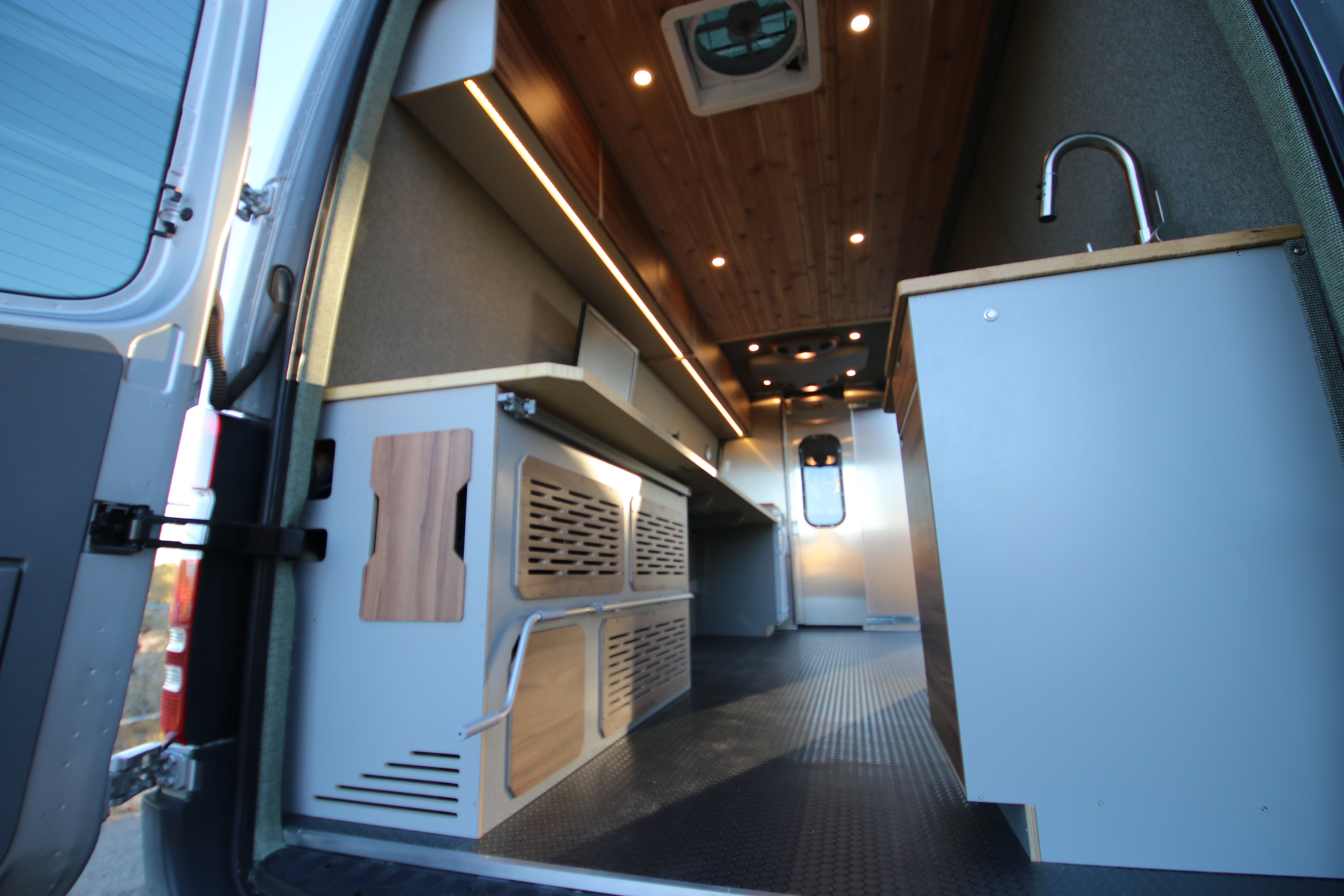Compact kitchenette with sink and storage inside custom Sprinter office van