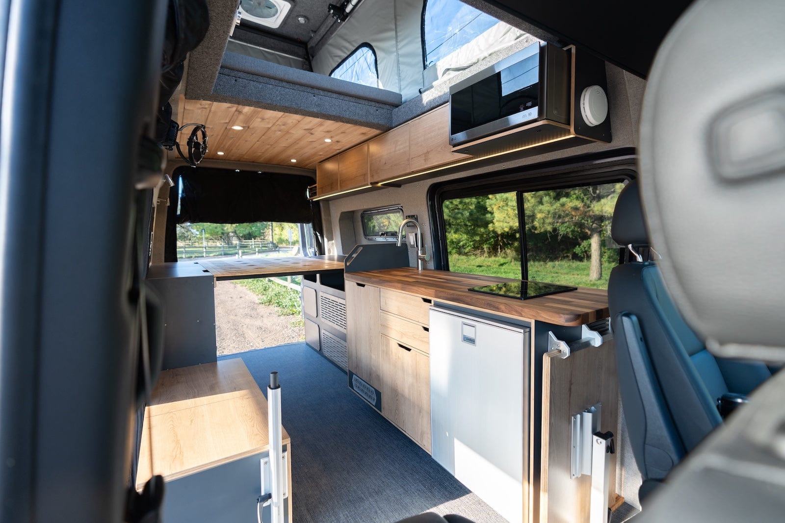 Interior of Luxury Sprinter Van Conversion by The Vansmith with Fine Wood Surfaces, Stove, Microwave and Pop-Top