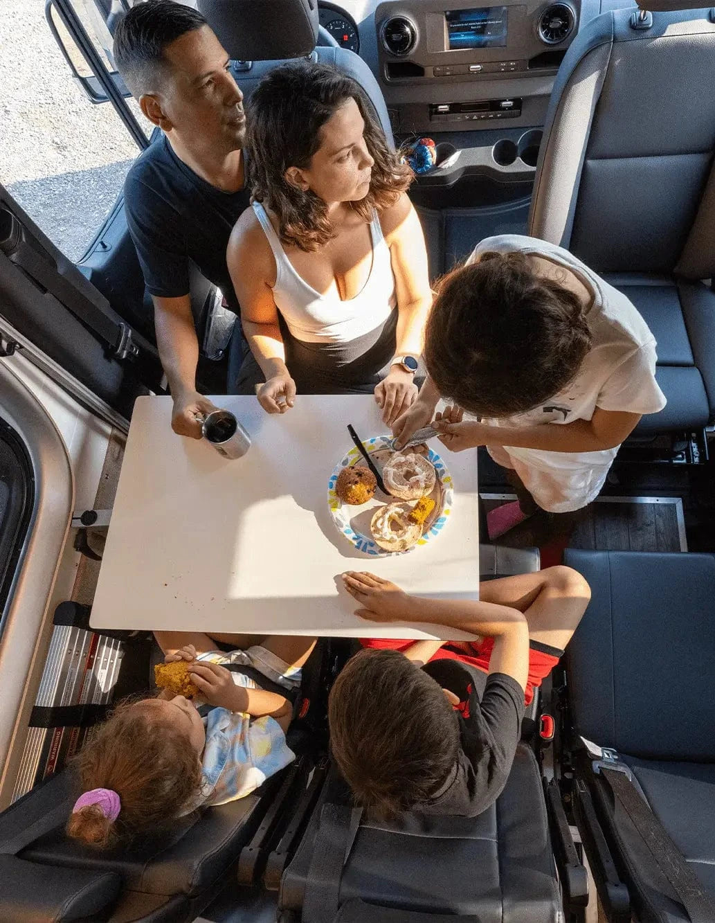 Family of Five Around Kitchen Galley Table in Custom Colorado Van Conversion by The Vansmith