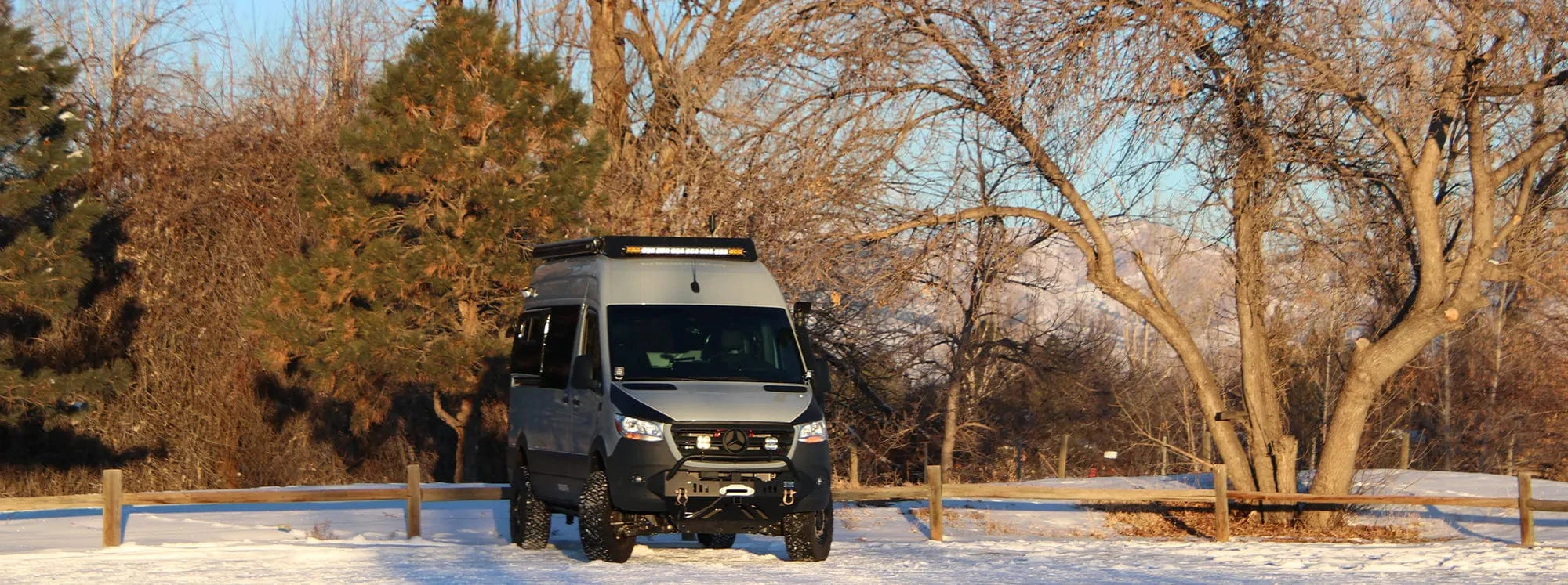 Exterior of Grey Sprinter Van Conversion by The Vansmith in Snow with Roof Rack and Off-Road Cladding