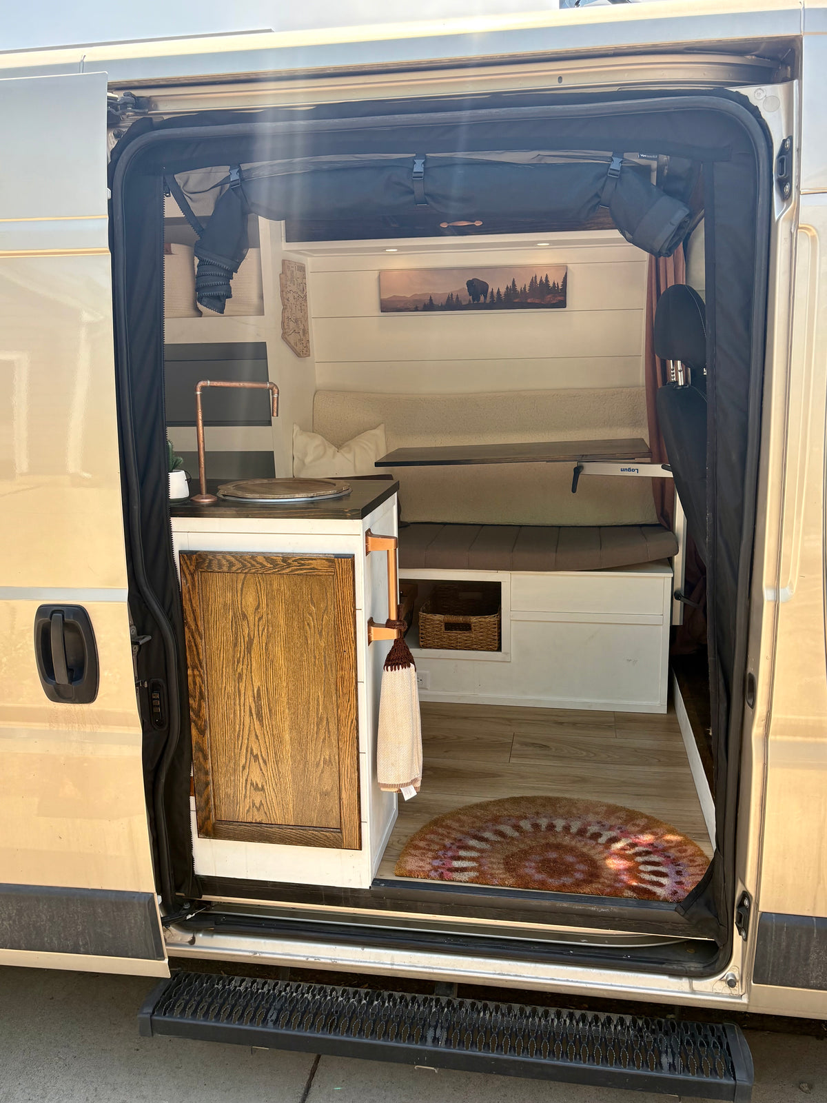 Sliding door open on the ProMaster camper showing the galley, sink and rear bed