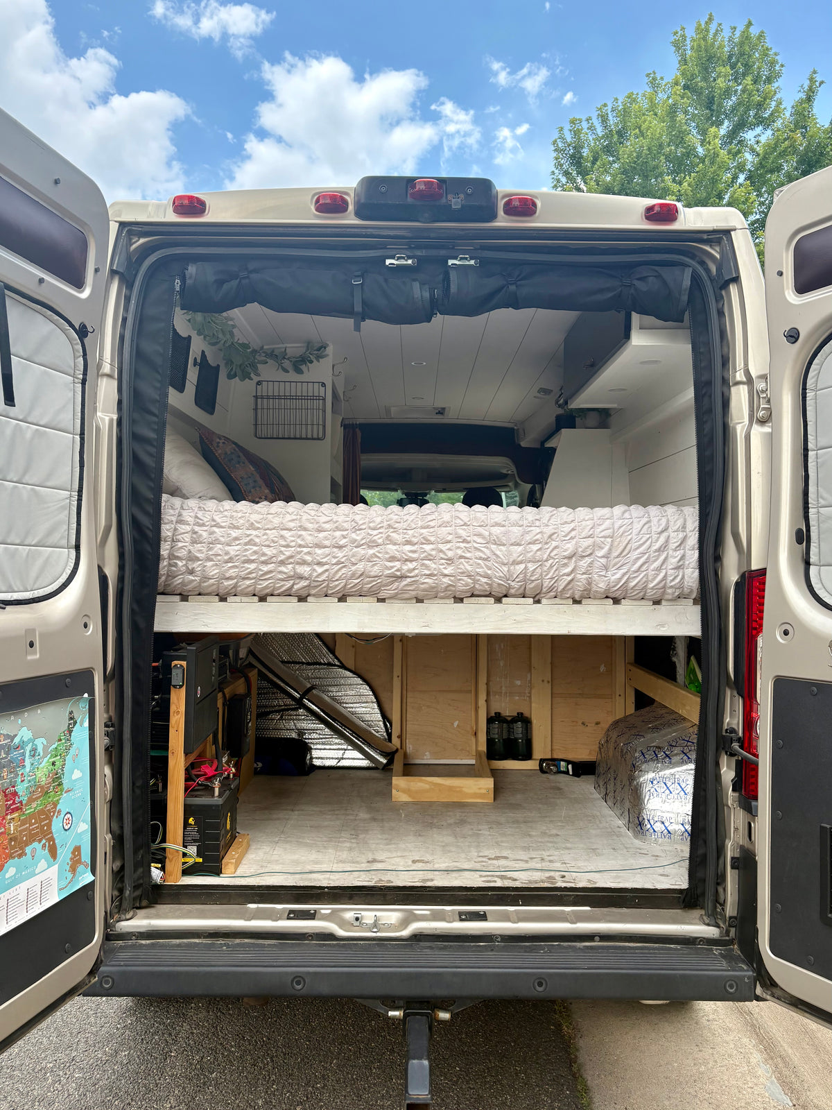 Rear doors open showing the fixed bed and rear gear garage of the ProMaster camper