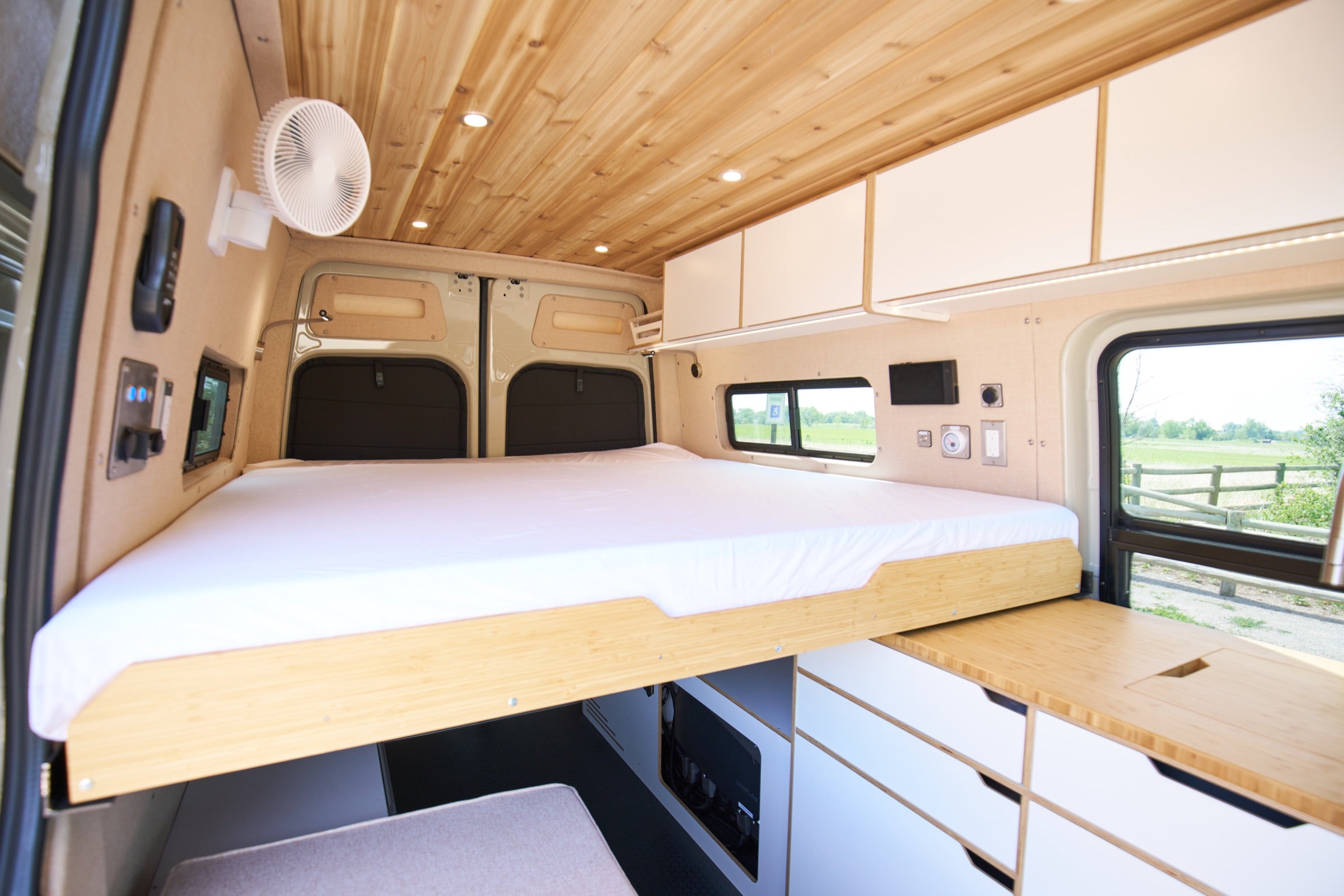 Rear bed of Sprinter Bivy Classic camper van viewed through open back doors - The Vansmith