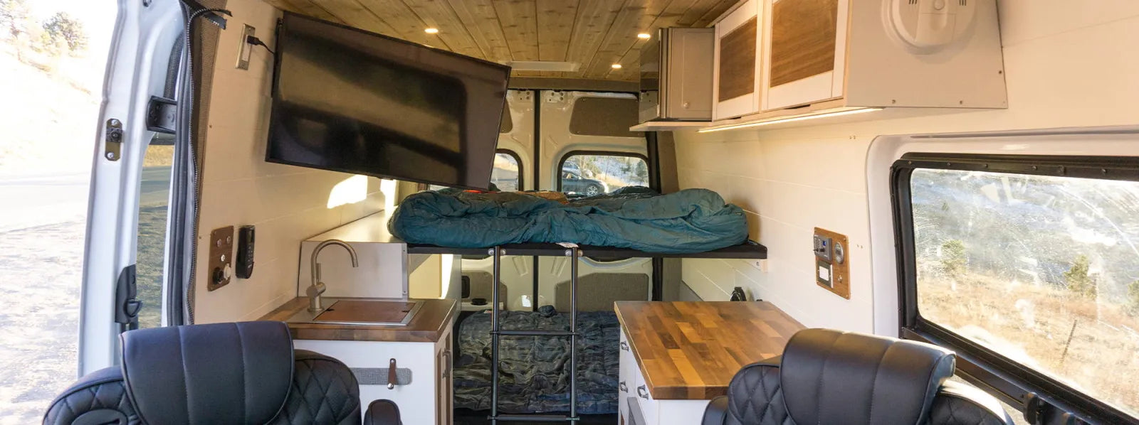 Ace Sprinter van conversion interior with walnut kitchen, swivel seats, and elevated bed by The Vansmith