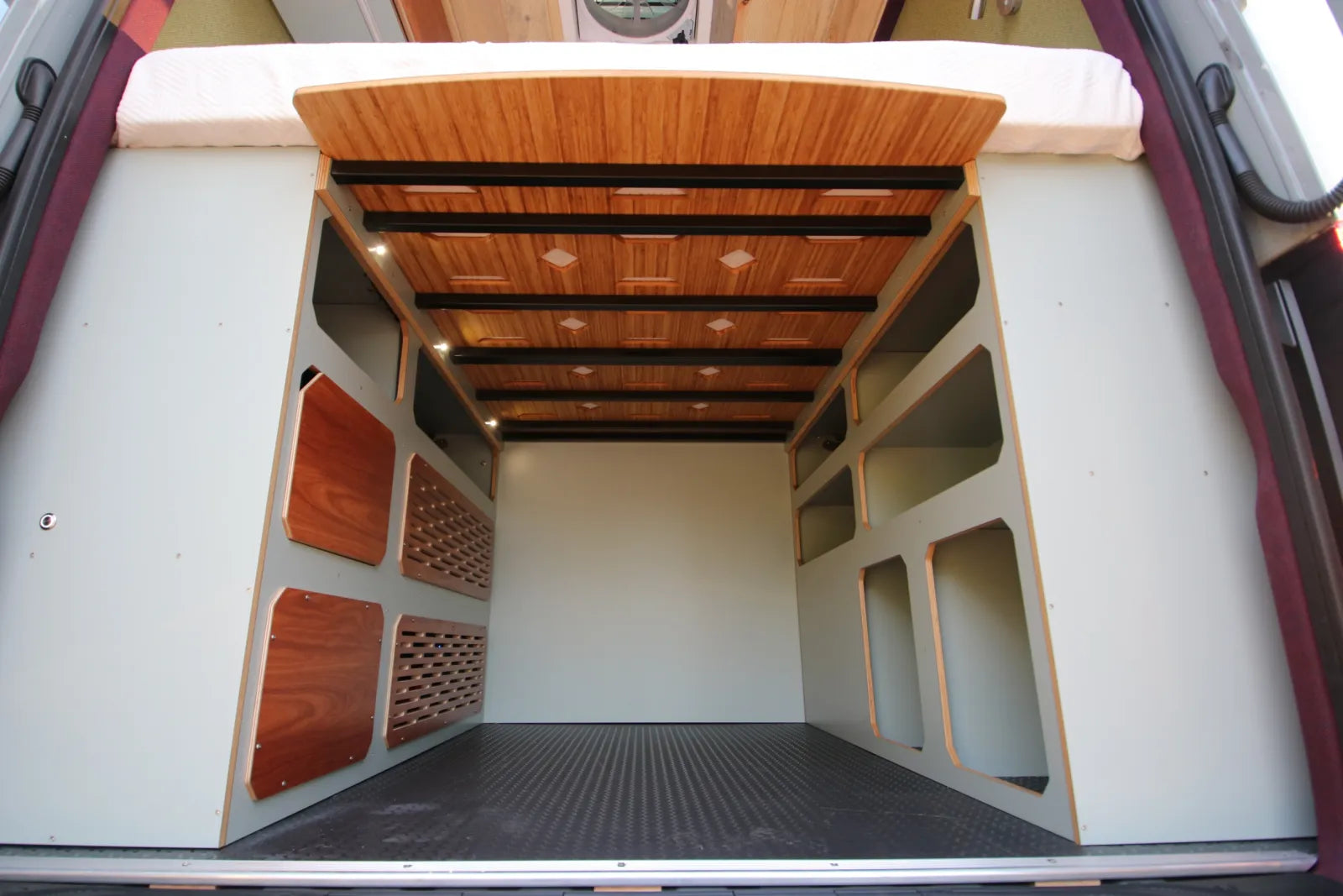 Under-bed garage storage with wine rack and custom shelving in AL van build by The Vansmith