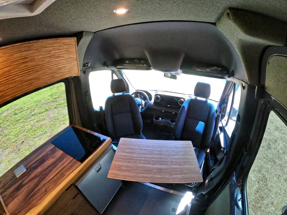 Bamboo van interior front cab view with fold-down walnut dining table and driver seats