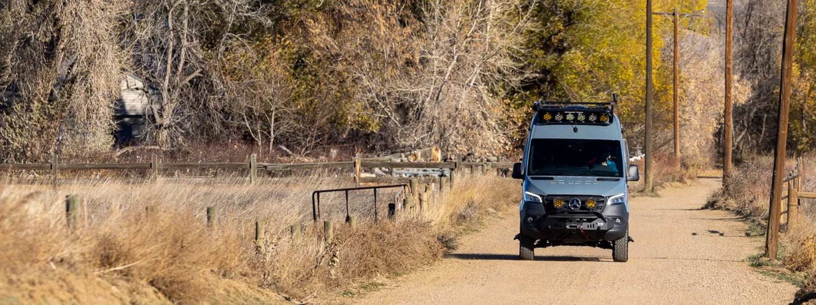 The Vansmith Crew Sprinter 144 4x4 van conversion with roof rack on a Colorado road