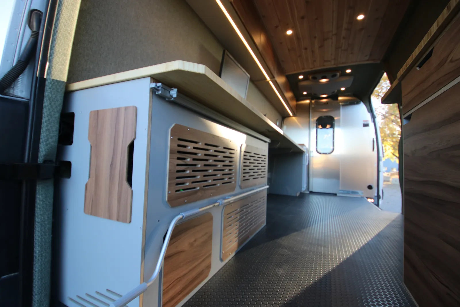 Hustle van conversion custom cabinetry with ventilated doors and walnut wood ceiling by The Vansmith