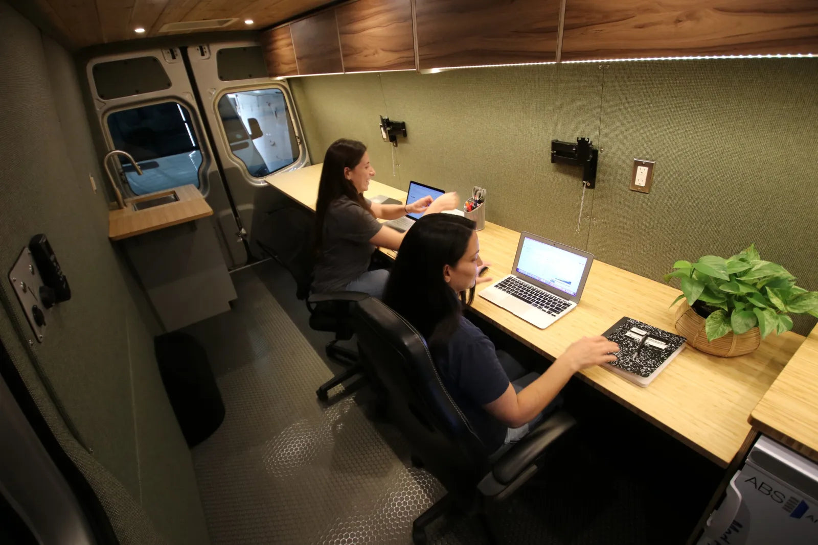 Hustle mobile office van with two ergonomic chairs laptops and desk plants by The Vansmith