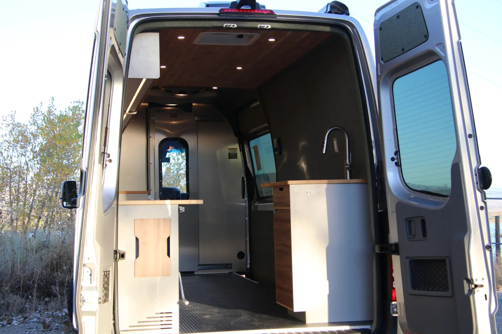 Hustle Sprinter van rear view with open doors showing sink cabinetry and workspace by The Vansmith