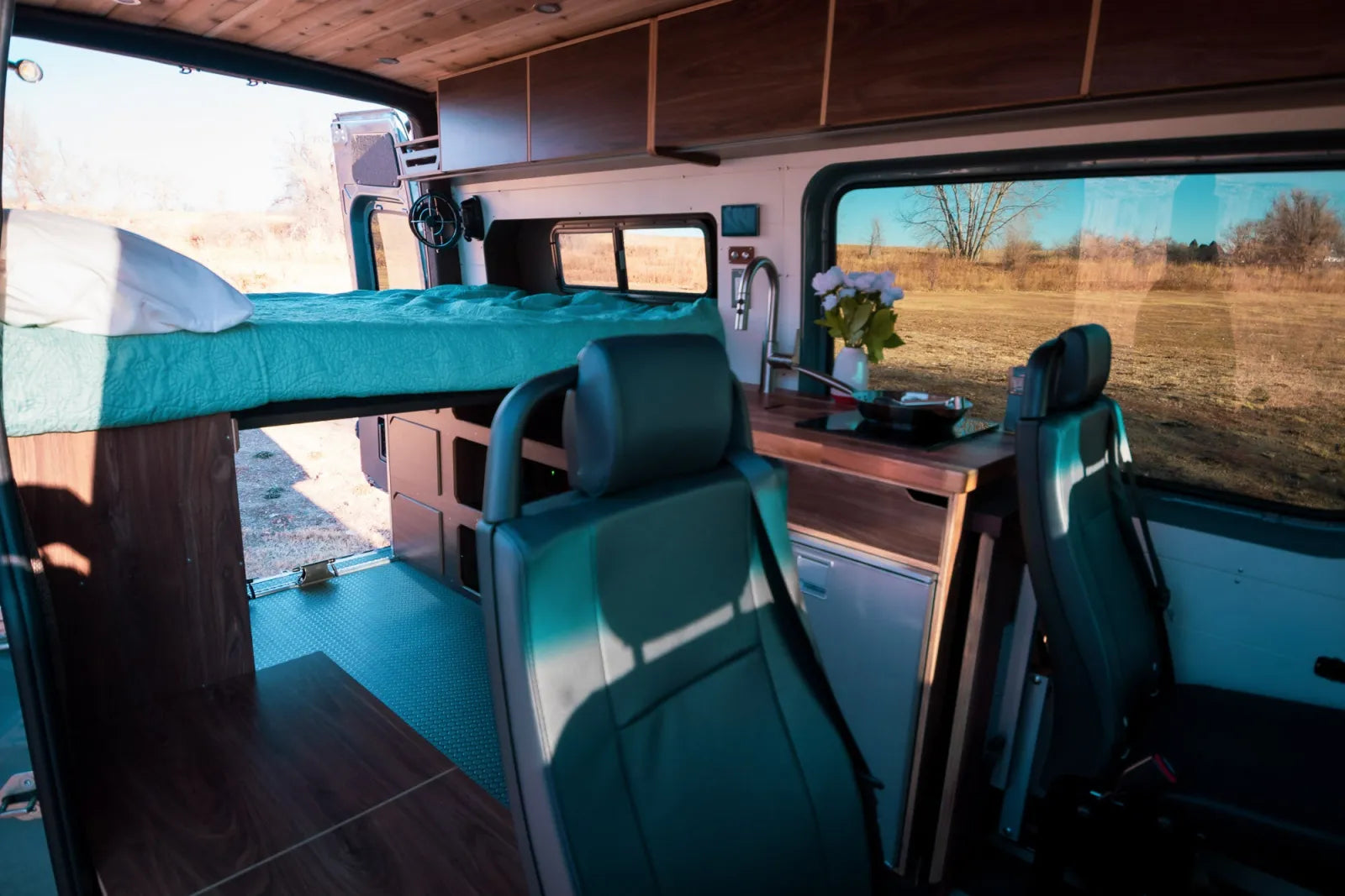 Jimmy Sprinter van interior wide view with four seats elevated bed and galley kitchen by The Vansmith