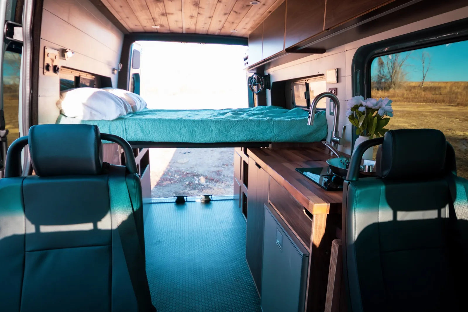 Jimmy van conversion full interior with elevated bed walnut kitchen and four seats by The Vansmith