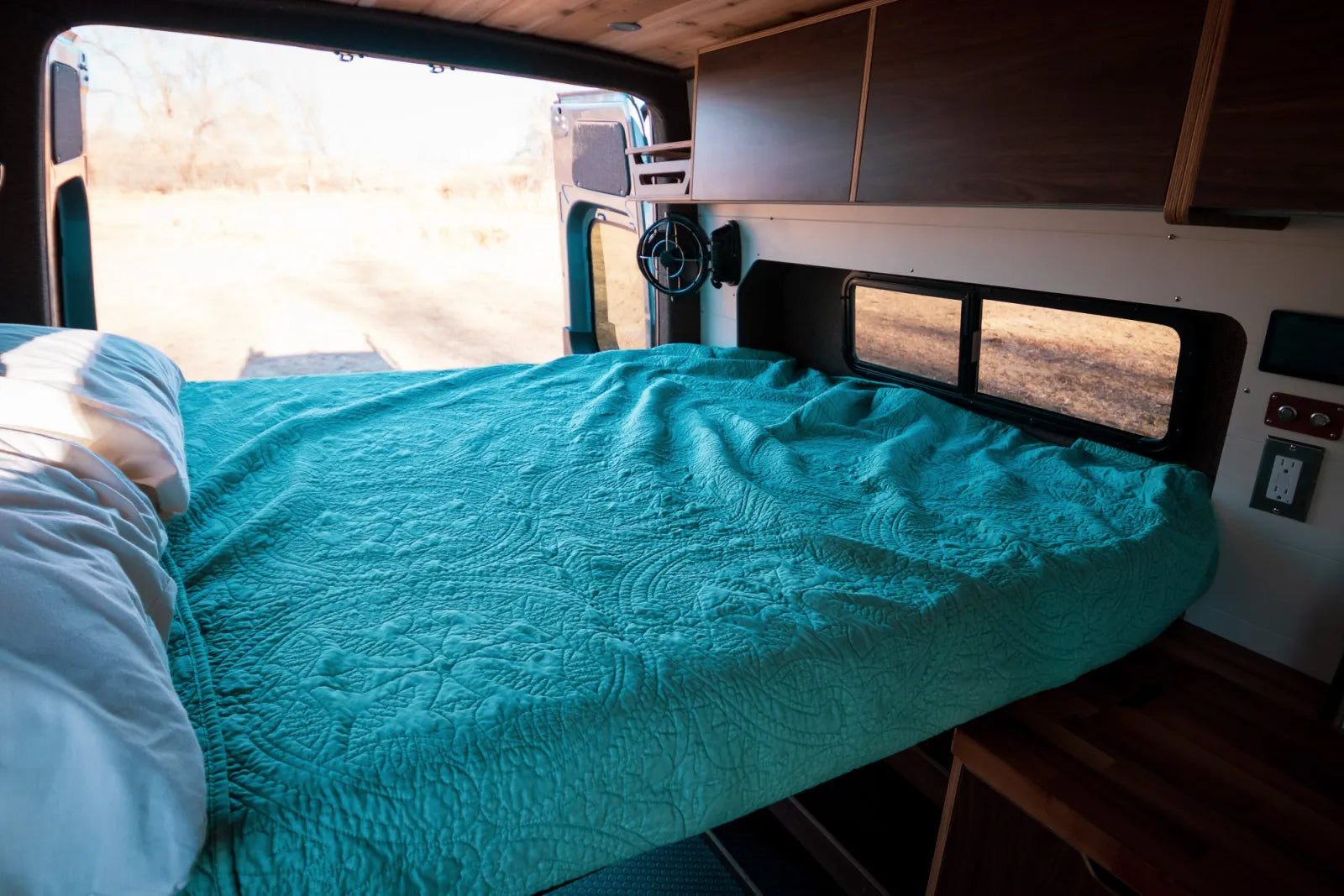 Jimmy Sprinter van queen bed platform with teal bedding and walnut ceiling by The Vansmith