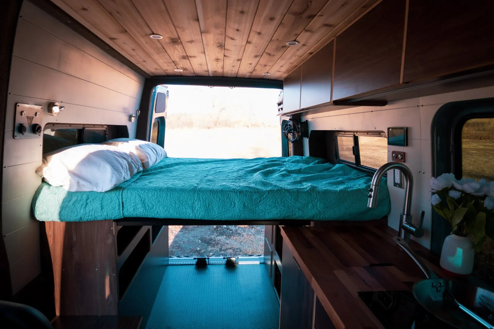 Jimmy van conversion elevated bed over kitchen with cedar ceiling and LED lighting by The Vansmith