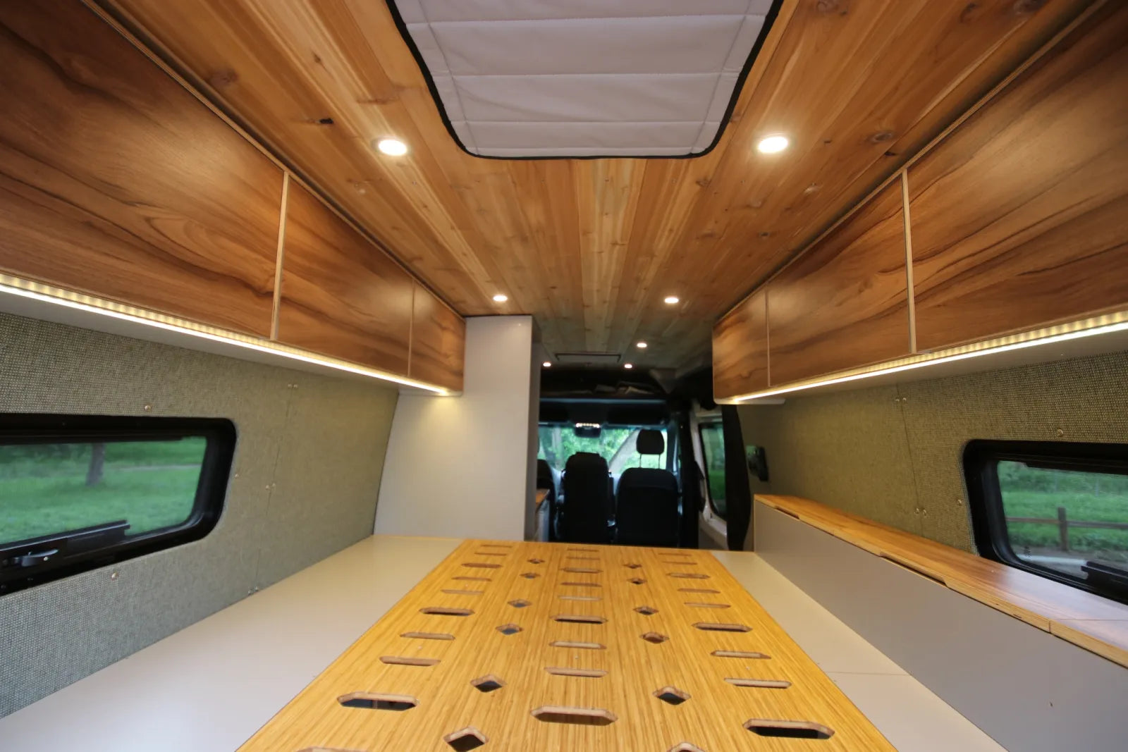 Maverick Sprinter van bed platform view with cedar ceiling LED strip lights and fan vent by The Vansmith