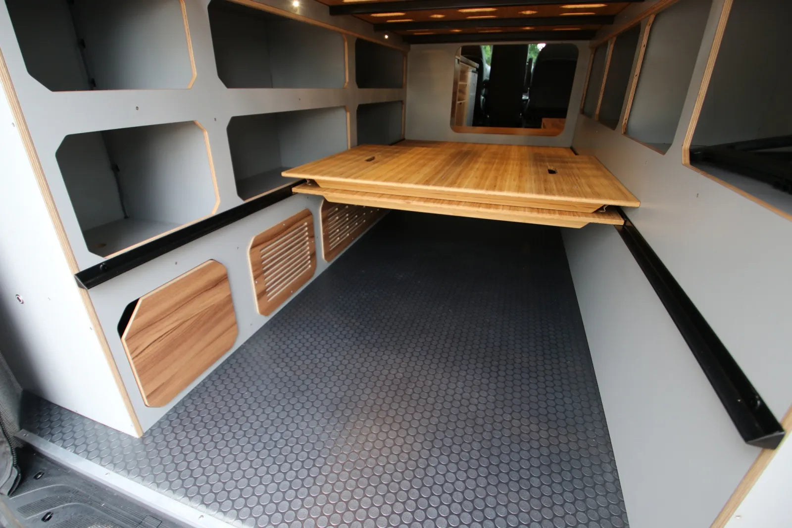 Maverick van conversion fold-out bamboo table with under-bed garage and hex floor by The Vansmith