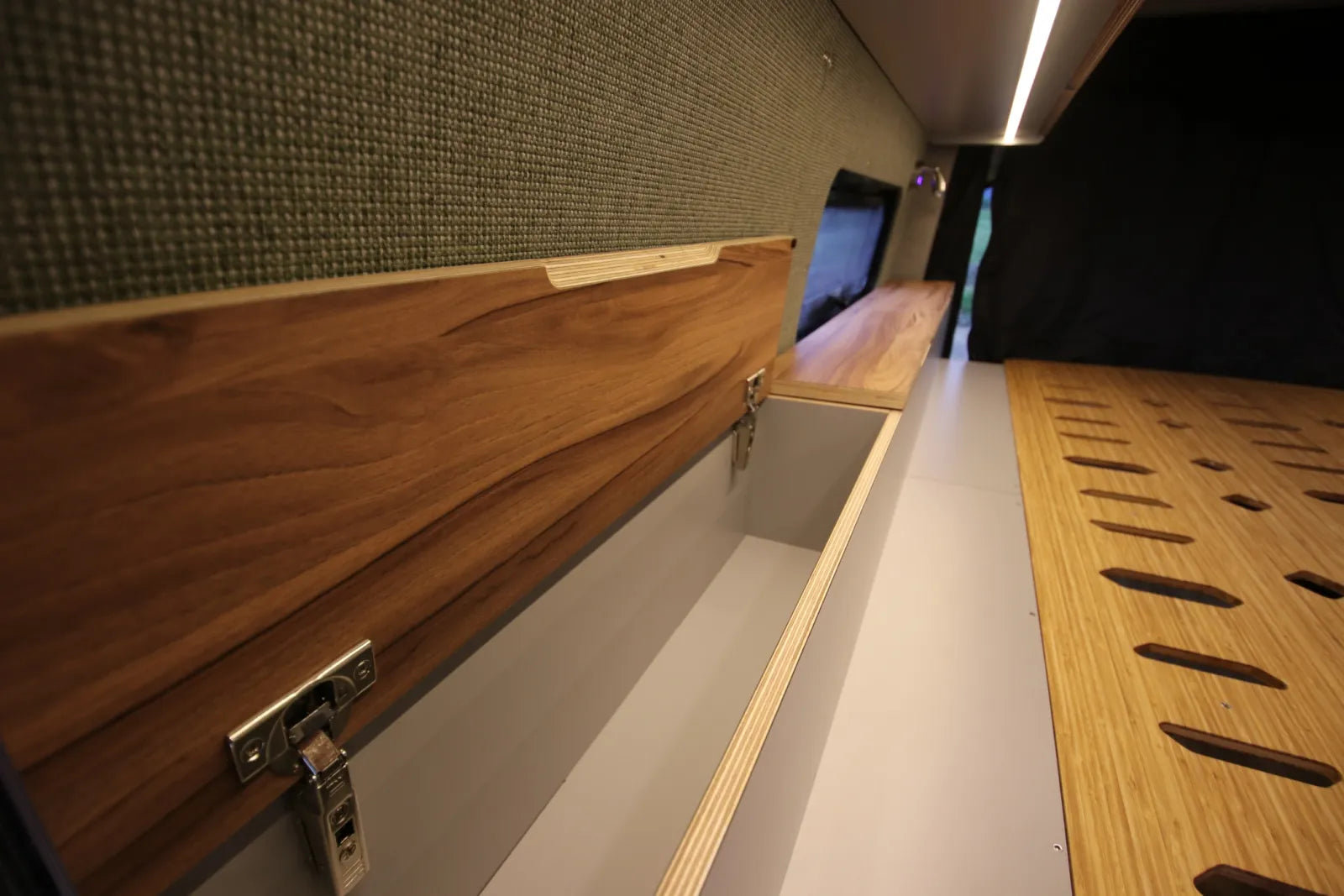 Maverick van conversion wall-mounted walnut storage cabinet with latches and bed slats by The Vansmith