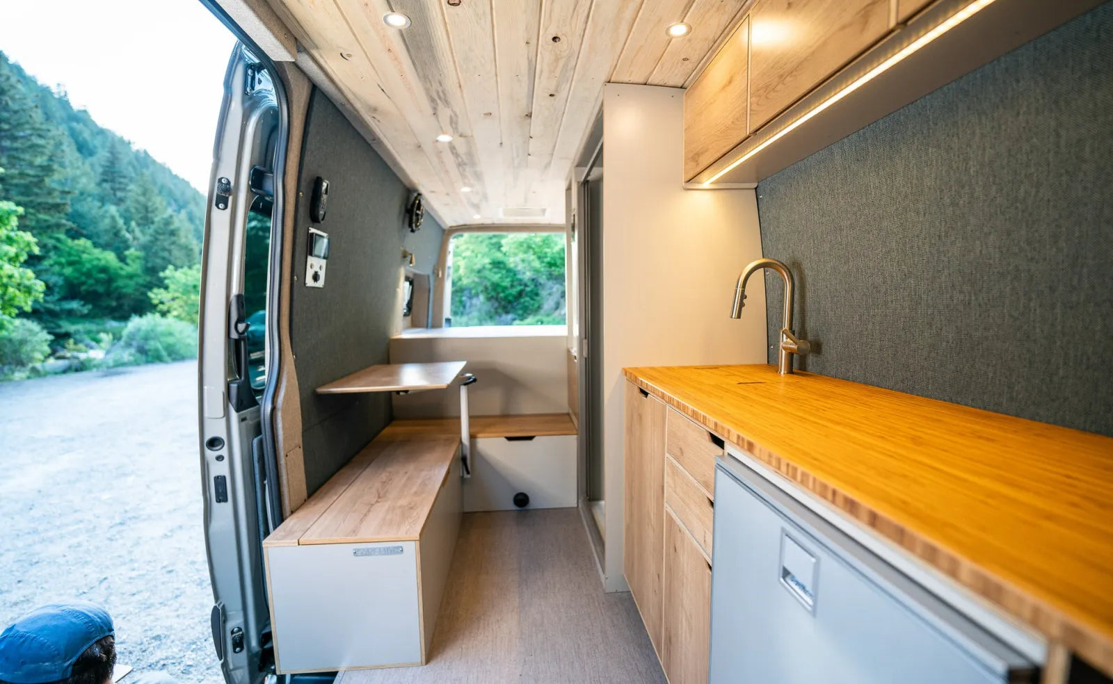 Outpost Sprinter interior with butcher block counter, bench seating, and sink