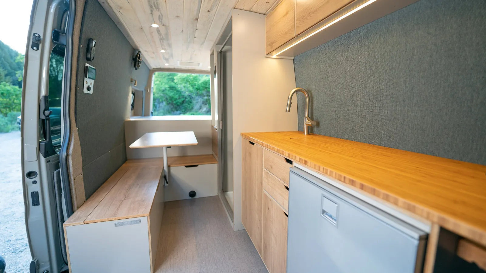 Outpost Sprinter interior with fold-up table, bench seating, and kitchen
