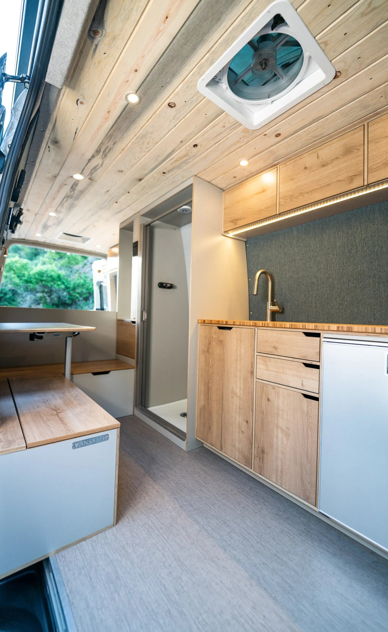 Outpost van MaxxFan vent with shower stall and oak kitchen cabinetry below