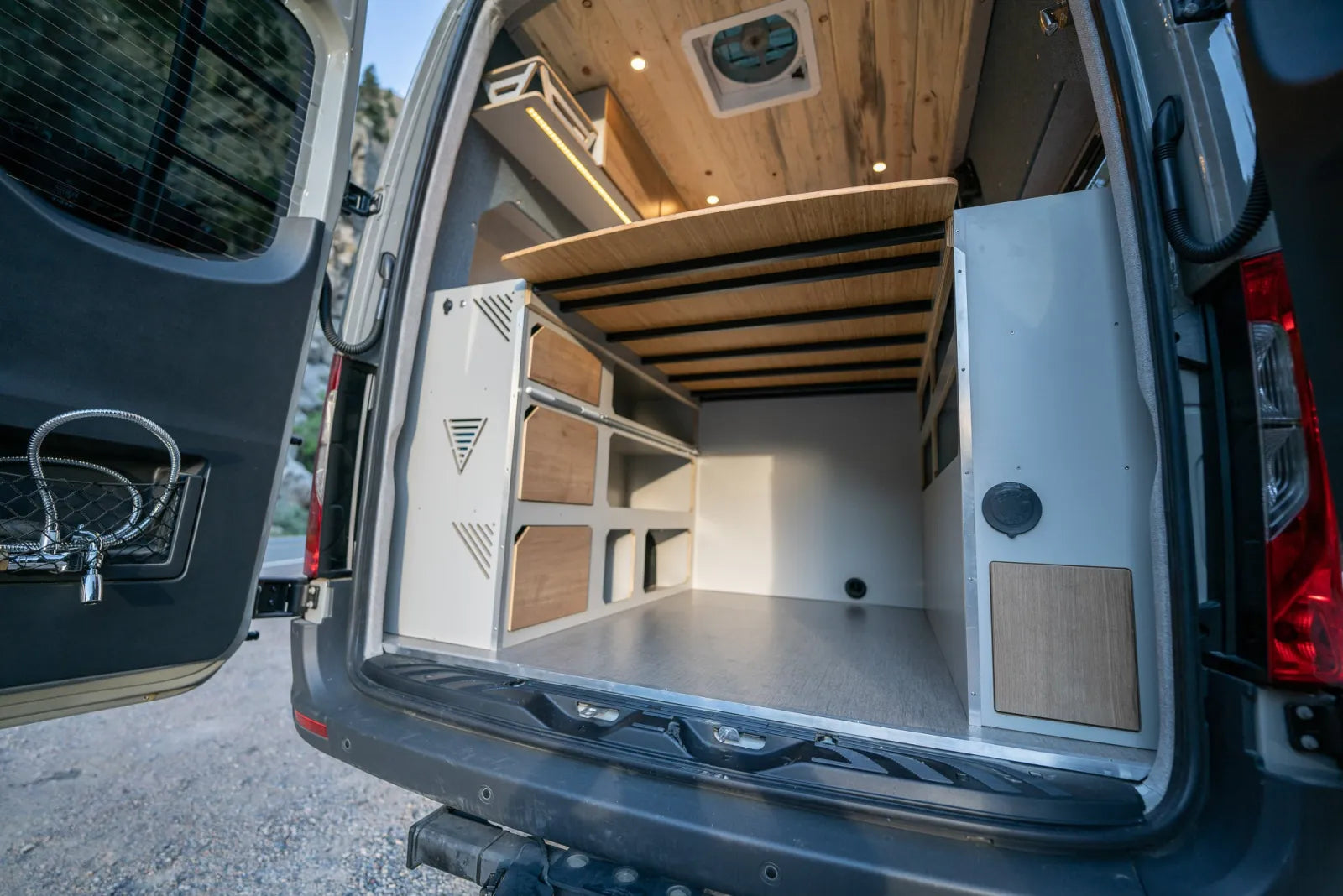 Outpost van rear doors open showing elevated bed platform and modular storage