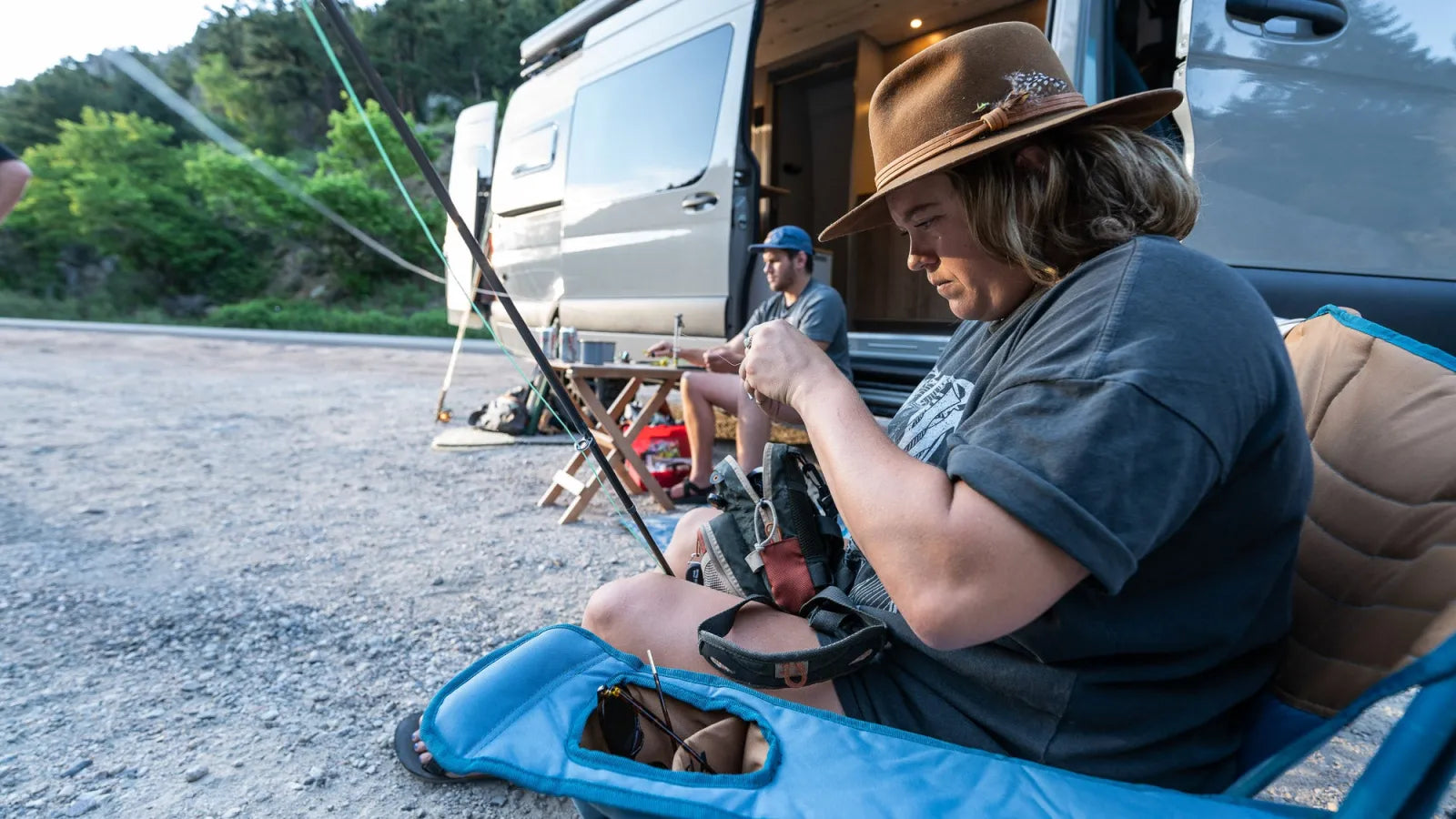 Woman preparing fly fishing gear outside Outpost Sprinter van in Colorado