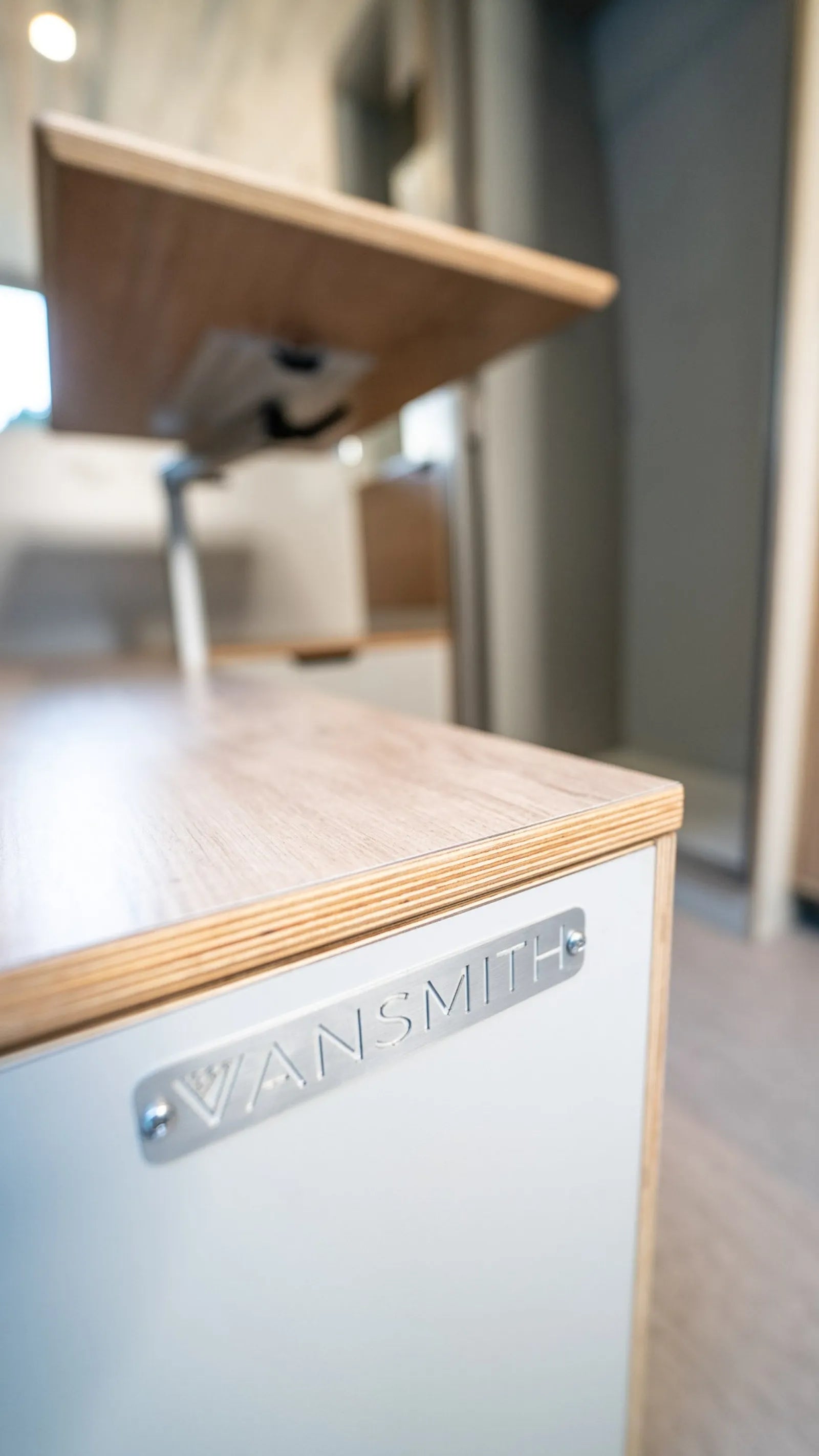 The Vansmith metal logo close-up on Outpost van conversion cabinetry