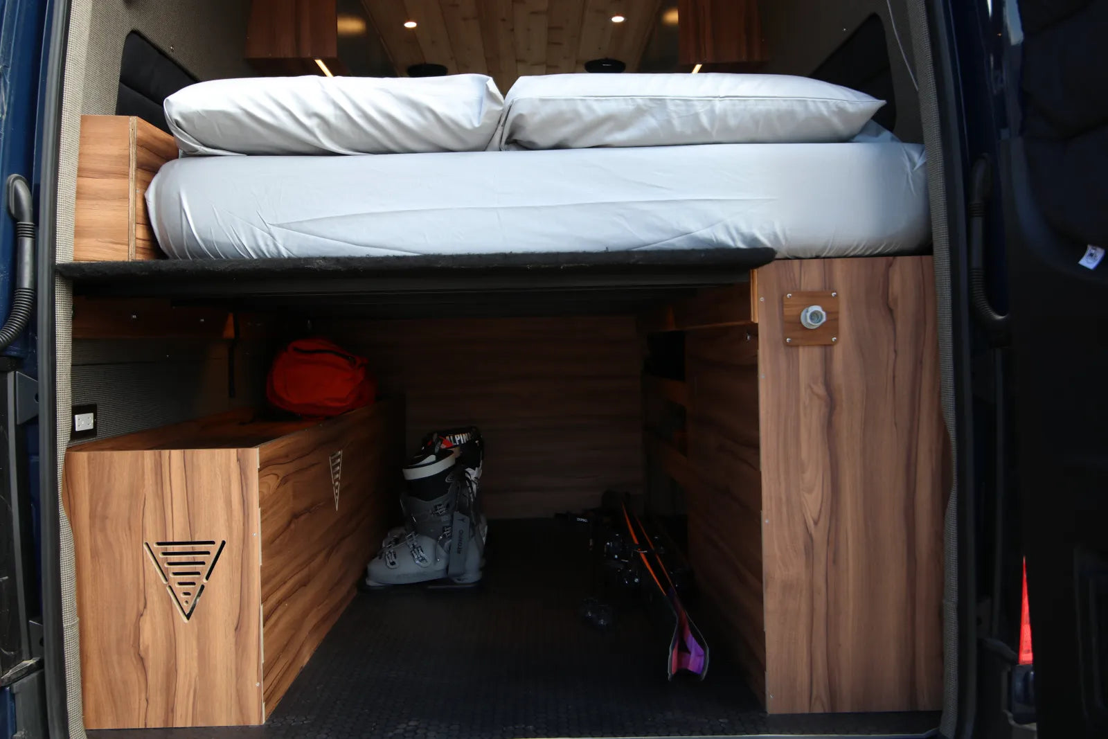 Rapp van rear with queen bed, ski boots in garage, and Vansmith logo
