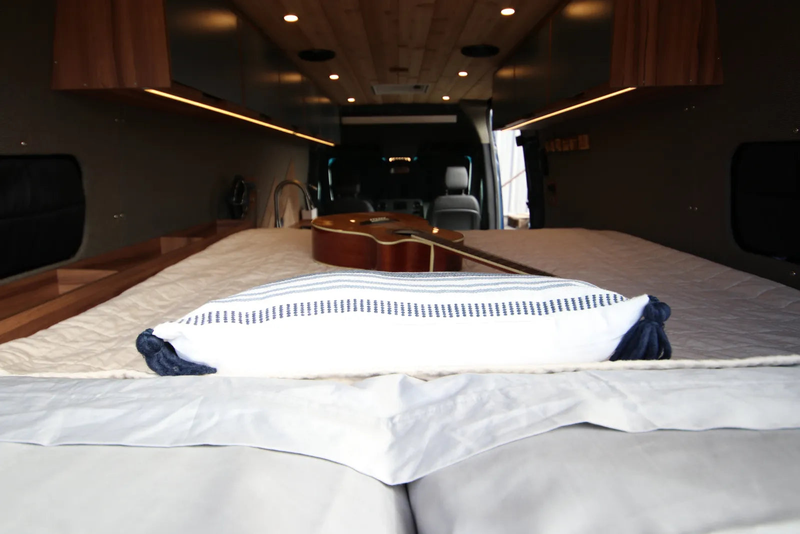 Rapp van queen bed with pillows and guitar looking forward through interior