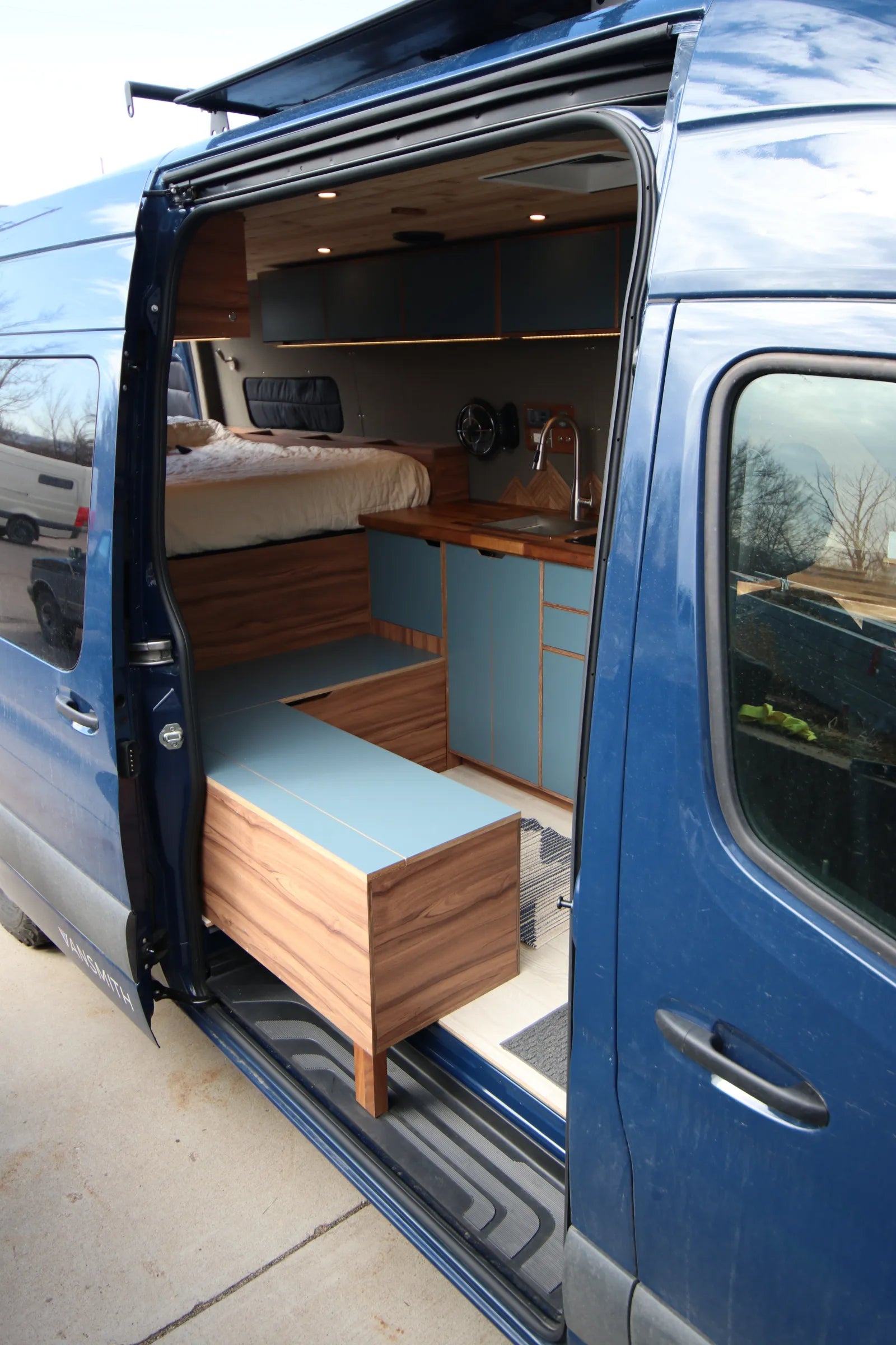 Rapp blue Sprinter side door open showing bench and kitchen interior
