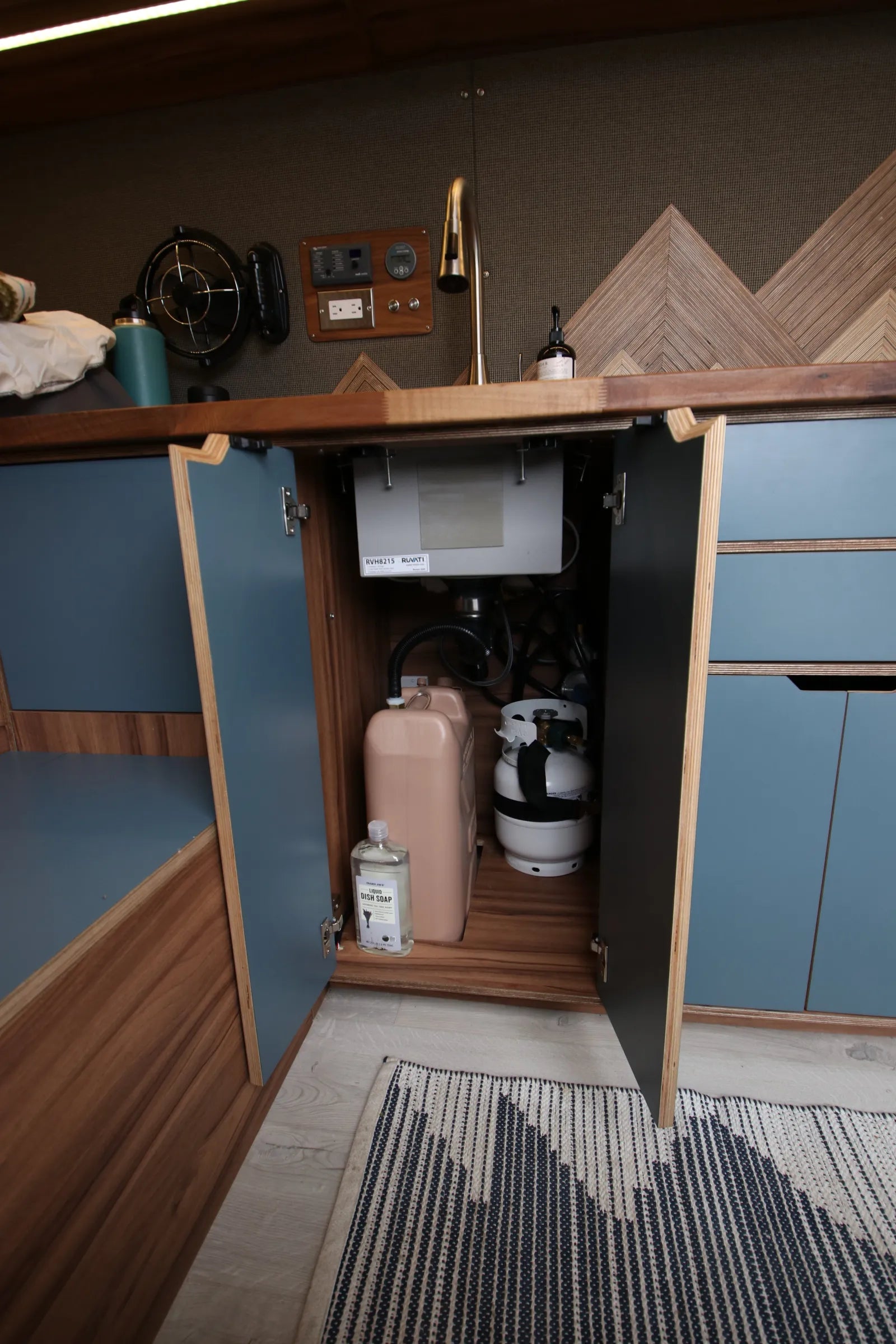 Rapp van under-sink cabinet open showing water tank and propane storage