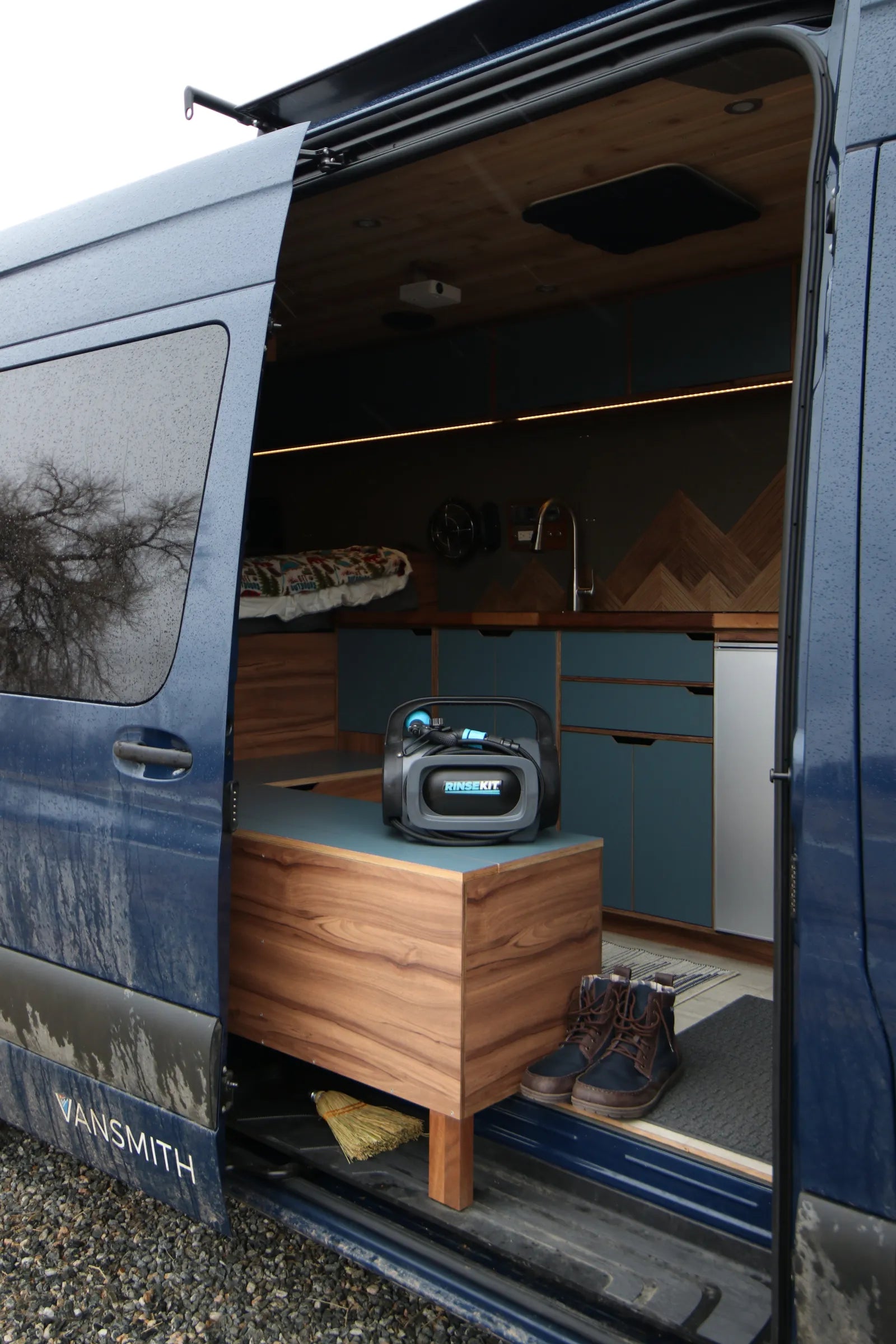 Rapp Sprinter side door view with walnut bench, kitchen, and mountain art