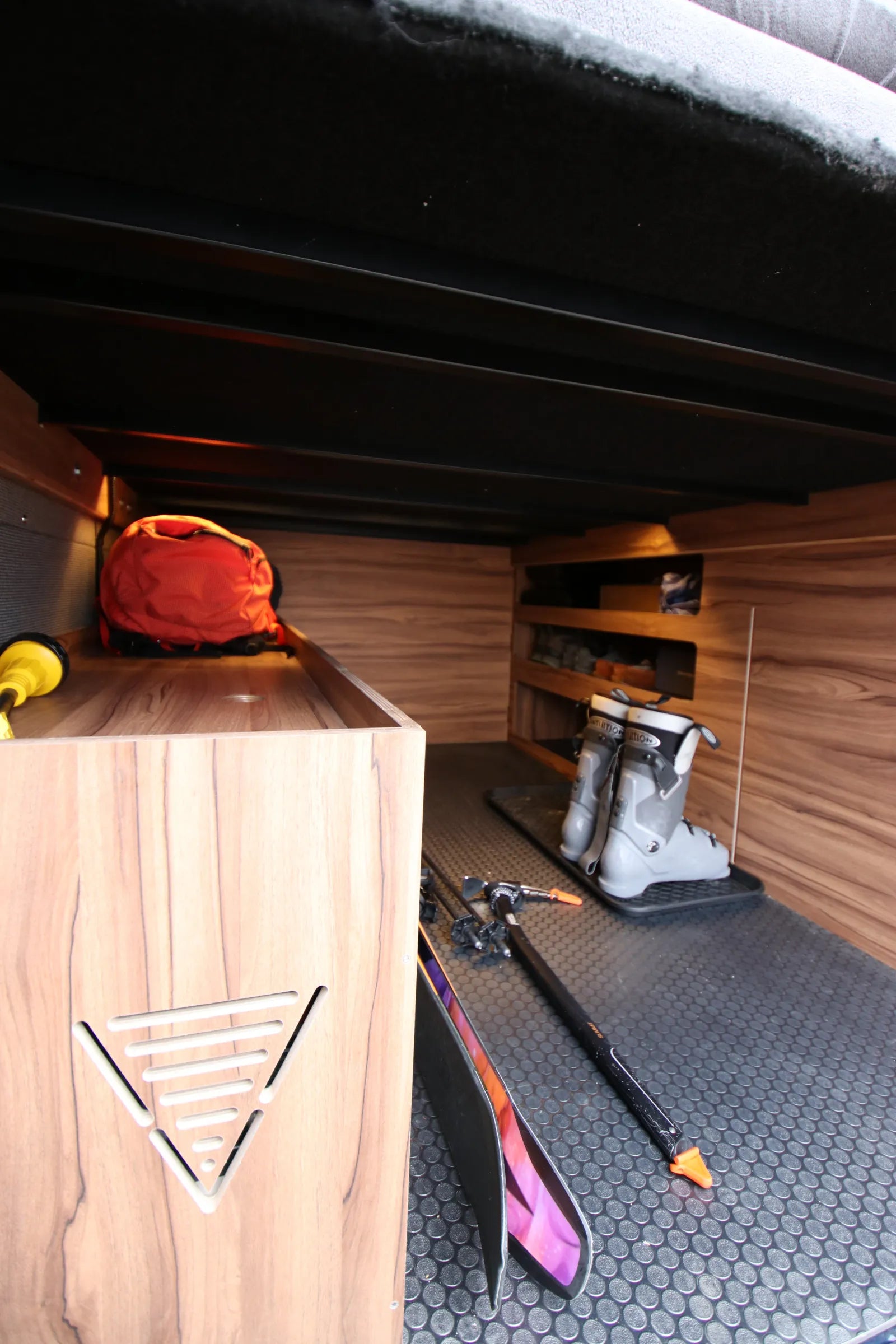 Rapp van under-bed garage with ski boots, poles, and walnut gear shelving